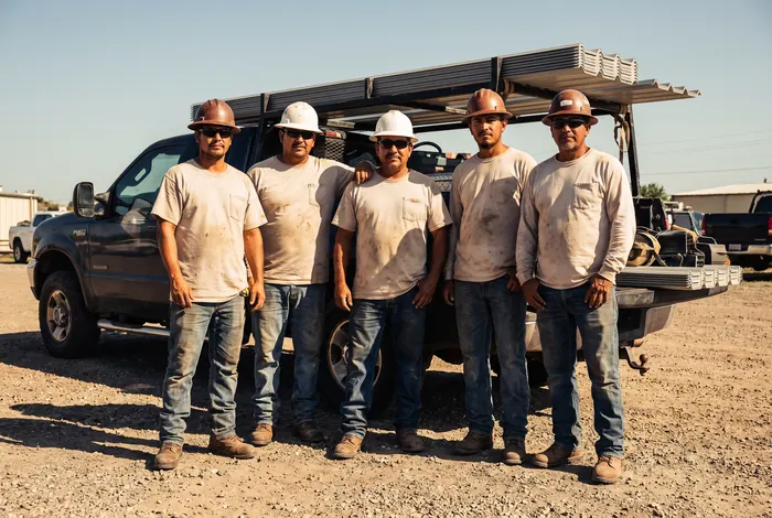 A five person roofing crew standing in front of a work truck